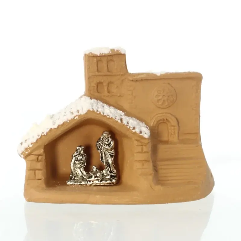 Mini crèche en terre cuite sous une église enneigée