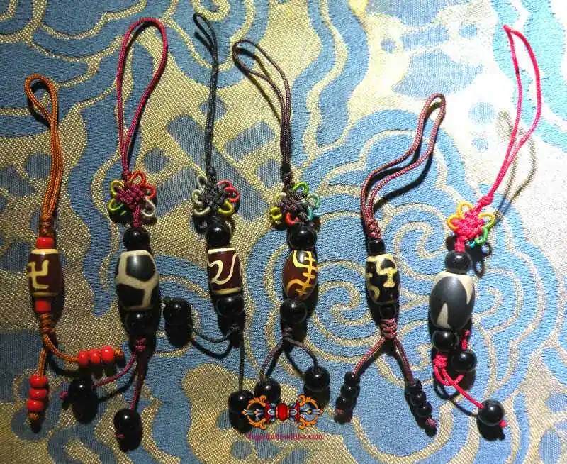 Small Tibetan Dzi mounted on silk thread - various models available.
