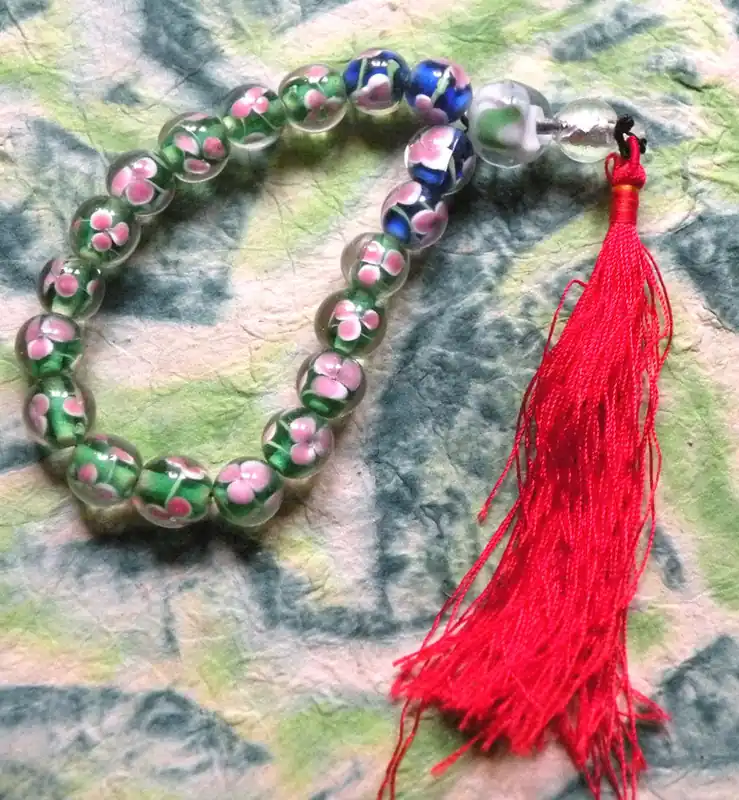Buddhist wrist rosary made of glass with floral decoration.