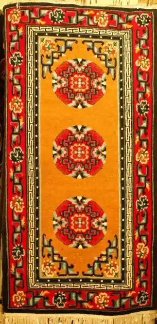 Tapis tibétain avec motif de pièces et bordure.